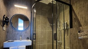 A modern bathroom with a glass-enclosed shower, a sink with a mirror, and a toilet. - Weingart Seaside Hotel (Istanbul)