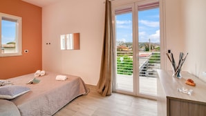 A bedroom with a bed, a desk, a window, and a view of a balcony. - Eclisse House Few Steps From The Sea (Augusta)