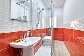 A modern bathroom with a glass shower enclosure, a white sink, and a toilet. - Eclisse House Few Steps From The Sea (Augusta)