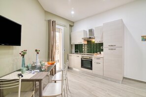 A modern kitchen with a dining area, a flat-screen TV, and a window with curtains. - Eclisse House Few Steps From The Sea (Augusta)