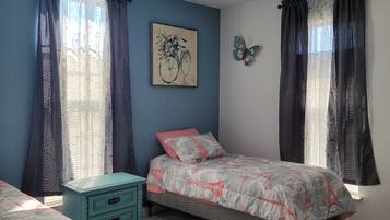 A bedroom with two beds, a dresser, a painting, and a butterfly wall decoration.