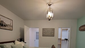 Een slaapkamer met een bed, een kroonluchter, een schilderij en een motiverende quote op de muur.