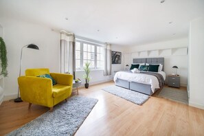 A modern bedroom with a bed, a yellow armchair, a large window, and a potted plant. - Livestay- Fabulous 1bed Apartment on Covent Garden (London)