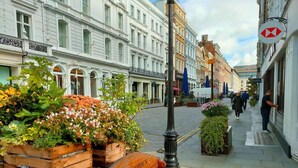 A street with a wooden bench labeled "COVENT GARDEN" and potted plants.