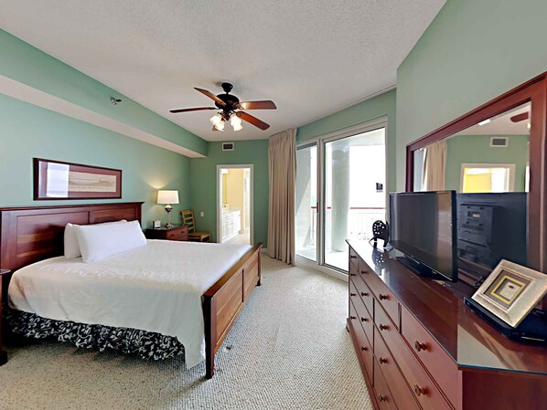 A hotel room with a bed, a dresser, a television, and a ceiling fan.