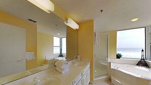 A modern bathroom with dual sinks, a large mirror, and a glass-enclosed shower. - Spacious Gulf Front Condo - Stunning Views + On-Site Amenities! (Navarre Beach)