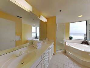 A modern bathroom with dual sinks, a large mirror, and a glass-enclosed shower.