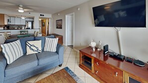 Una sala de estar con televisor, sofá y mueble bajo de madera.