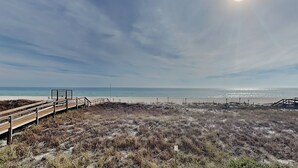 Una playa con un paseo marítimo de madera que lleva a una plataforma de observación.