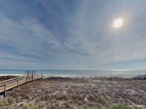 A beach with a wooden boardwalk leading to a viewing platform.