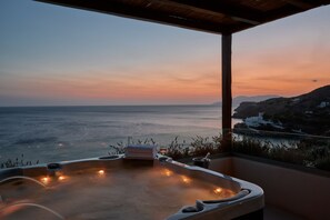 Un jacuzzi con vista al atardecer, una toalla y una copa de vino en un balcón.