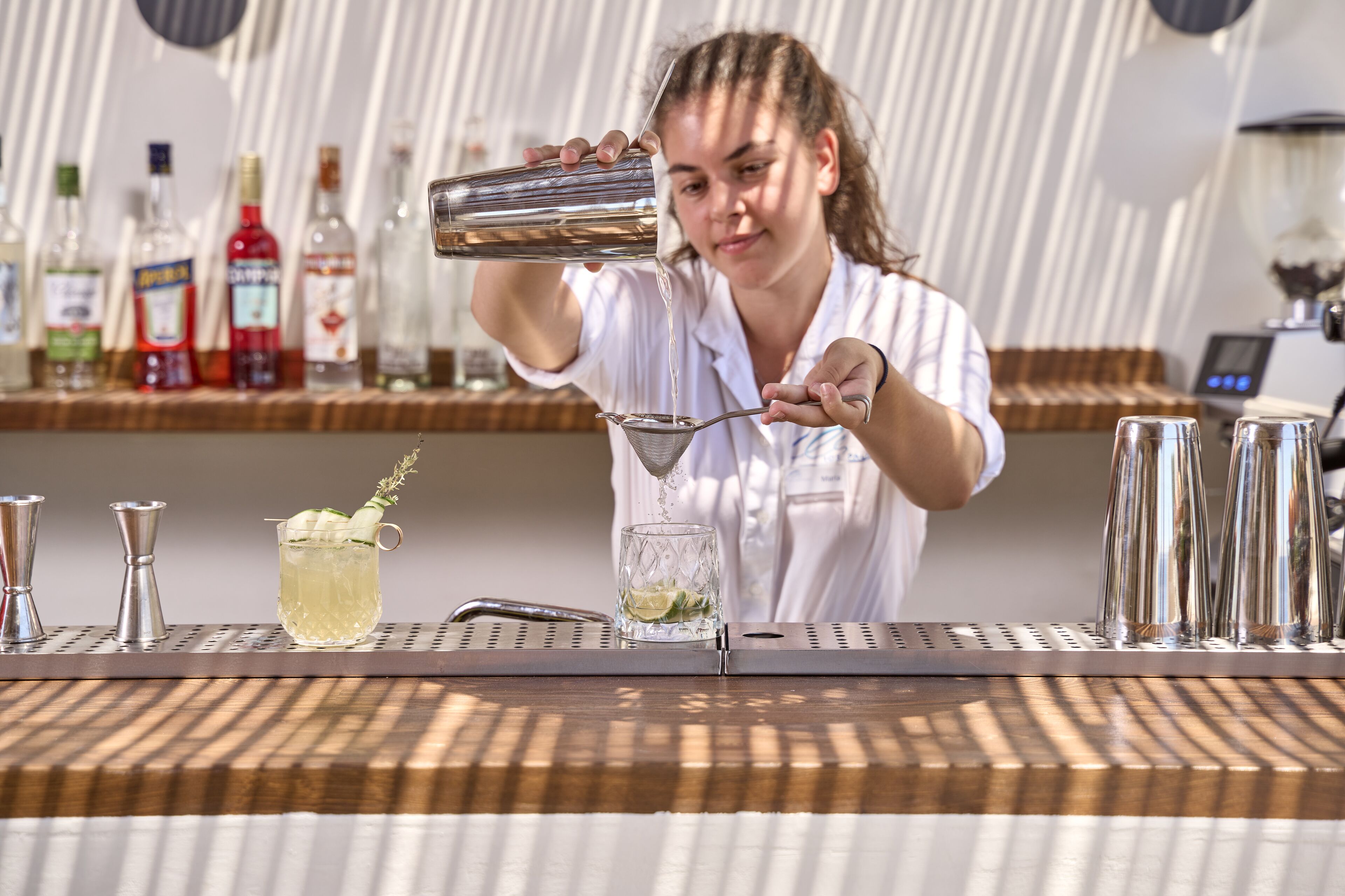 A bartender pouring a drink into a glass.