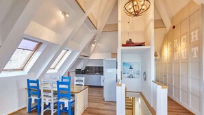 A spacious loft with high ceilings, skylights, a kitchen area, and a staircase leading to an upper level. - Host & Stay | The Watchtower (Waren Mill)