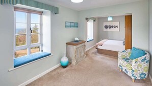 A bedroom with a large window, a bed, a bedside table, a chair, and a vase. - Host & Stay | The Watchtower (Waren Mill)