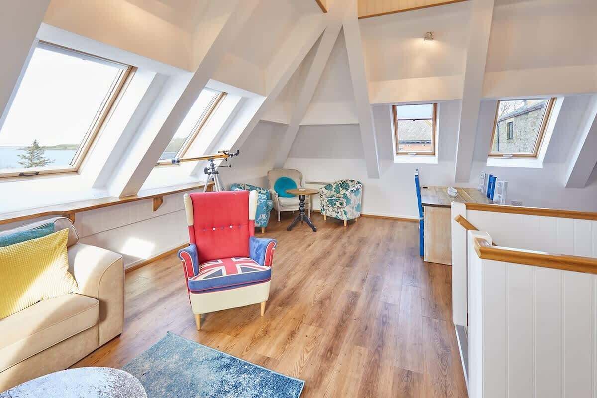Un loft moderno con lucernari, una poltrona rossa, un divano e un tavolino.
