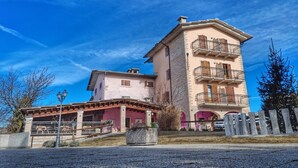 A multi-story building with a pink facade, a balcony on the upper floor, and a stone base. - Hotel Piccola Mantova (Bosco Chiesanuova)