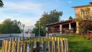 A circular stone structure in a grassy area with a building in the background. - Hotel Piccola Mantova (Bosco Chiesanuova)