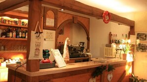 A bar area with wooden beams, shelves of bottles, a coffee machine, and a menu board. - Hotel Piccola Mantova (Bosco Chiesanuova)