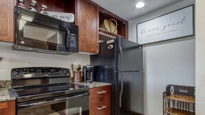 A kitchen with a microwave, stove, refrigerator, wooden cabinets, and a coffee maker. - Gorgeous 2BD/2BTH Condo w/ ∆ Views Pool Hot Tub Game Room 1/4 Mi to Parkway (Pigeon Forge)