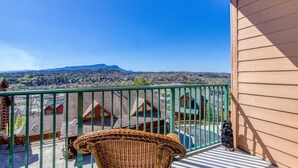 A balcony with a wicker chair, a view of houses and a mountain in the background. - Gorgeous 2BD/2BTH Condo w/ ∆ Views Pool Hot Tub Game Room 1/4 Mi to Parkway (Pigeon Forge)