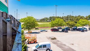A parking lot with vehicles, a building with a green facade, and trees in the background. - 127th Bayside-pool-short walk 2 beach-By Park! (Ocean City)