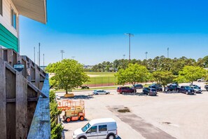 A parking lot with vehicles, a building with a green facade, and trees in the background. - 127th Bayside-pool-short walk 2 beach-By Park! (Ocean City)
