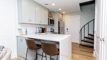 A kitchen with a central island, bar stools, a microwave, and a refrigerator.