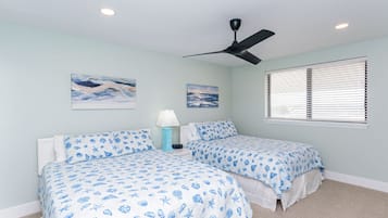 A bedroom with two beds, a ceiling fan, and artwork on the walls.