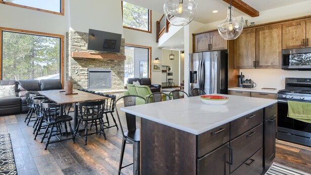 A spacious kitchen with a large island, wooden cabinets, and a stone fireplace. - New 3-Level Lodge w/ Amazing View Close to Slopes & Trails w/ Great Amenities (Lead)