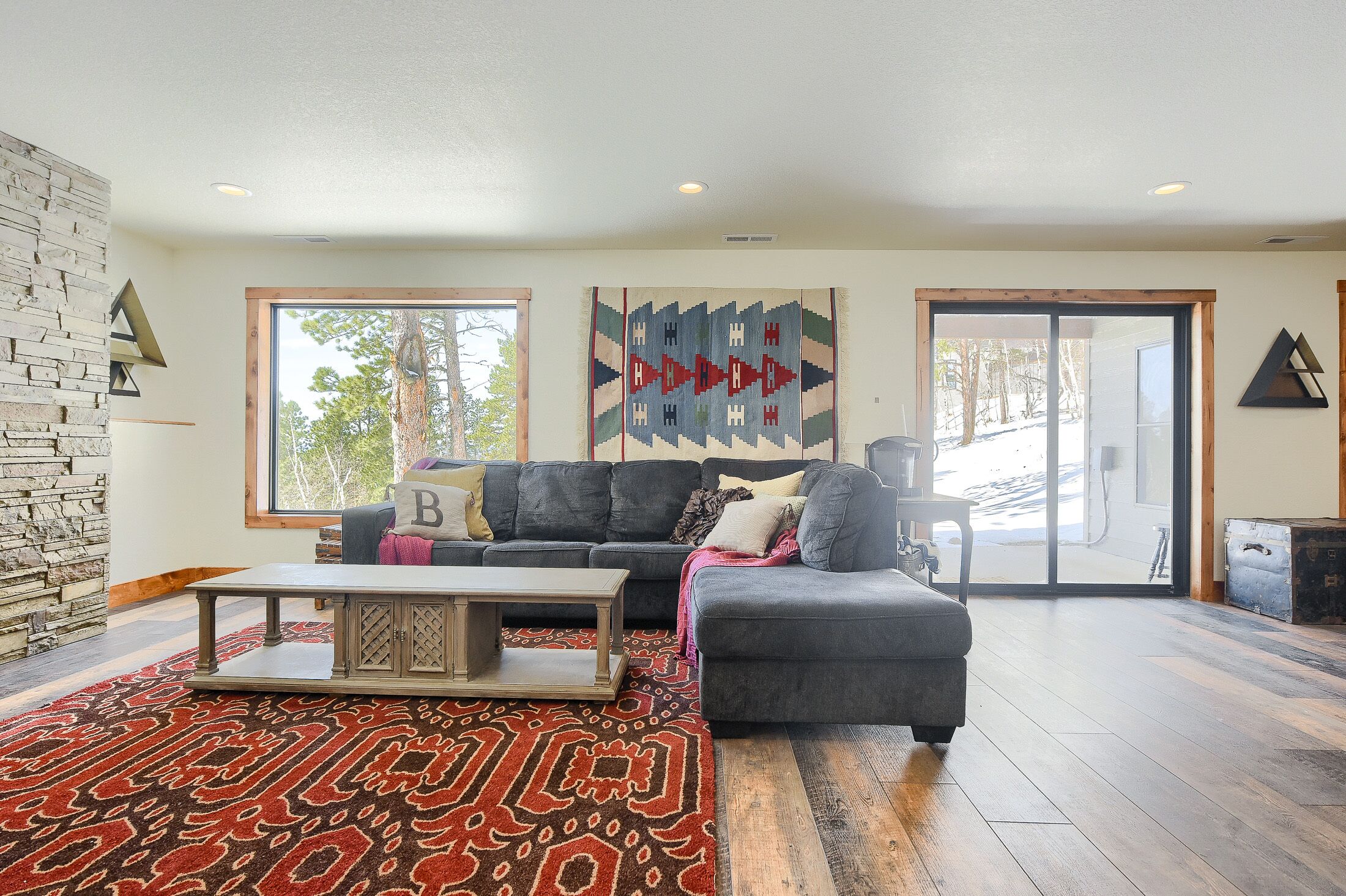 A modern living room with a gray sofa, a wooden coffee table, and a patterned rug.