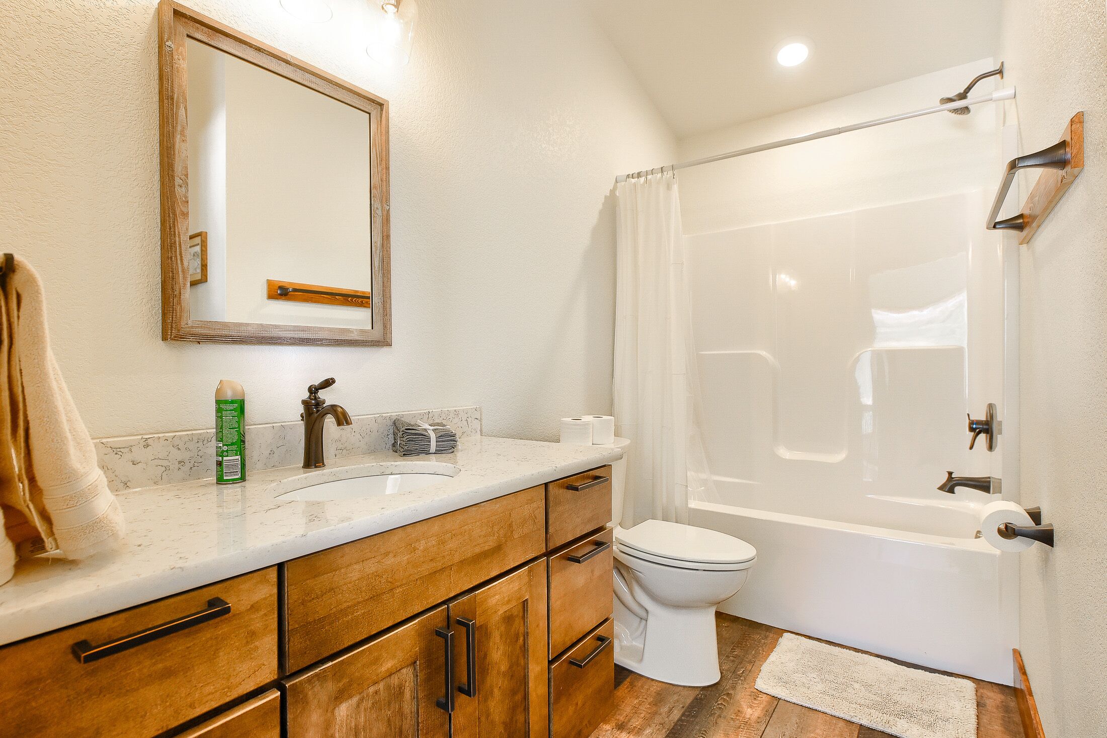 A bathroom with a wooden vanity, a white toilet, and a shower with a glass door.