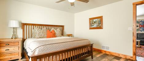 A bedroom with a wooden bed, a nightstand, a lamp, and a ceiling fan.