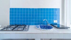 A kitchen with a gas stove, a sink with a blue backsplash, and a window. - THE STACKS 3 (Lido di Noto)