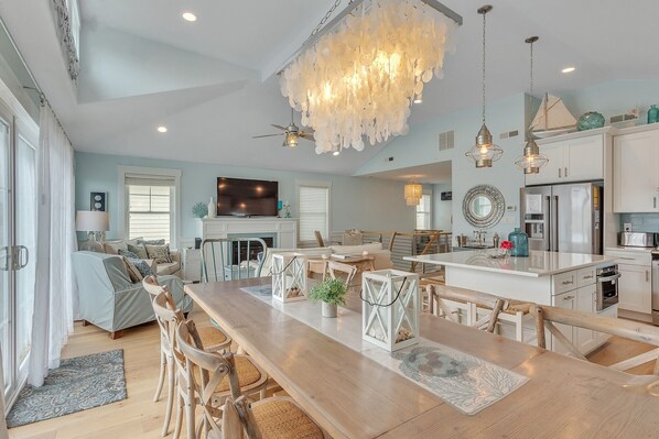 A spacious kitchen with a central island, modern appliances, and a dining area with wooden chairs and a long table.