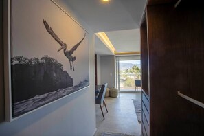 En gang med et stort muralmaleri af en fugl i flugt, et spiseområde med bord og stole, og udsigt til en balkon med udendørs natur.