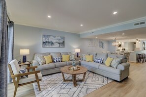 A modern living room with a sectional sofa, a round coffee table, and a dining area in the background.