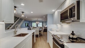 A modern kitchen with white cabinetry, a built-in oven, and a microwave. - Sunset Rentals | Shipmaster 1203 (Hilton Head Island)