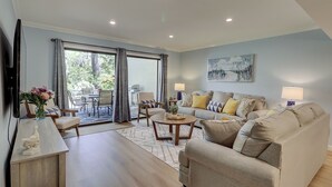 A spacious living room with a sofa, coffee table, and a dining area with chairs and a table. - Sunset Rentals | Shipmaster 1203 (Hilton Head Island)