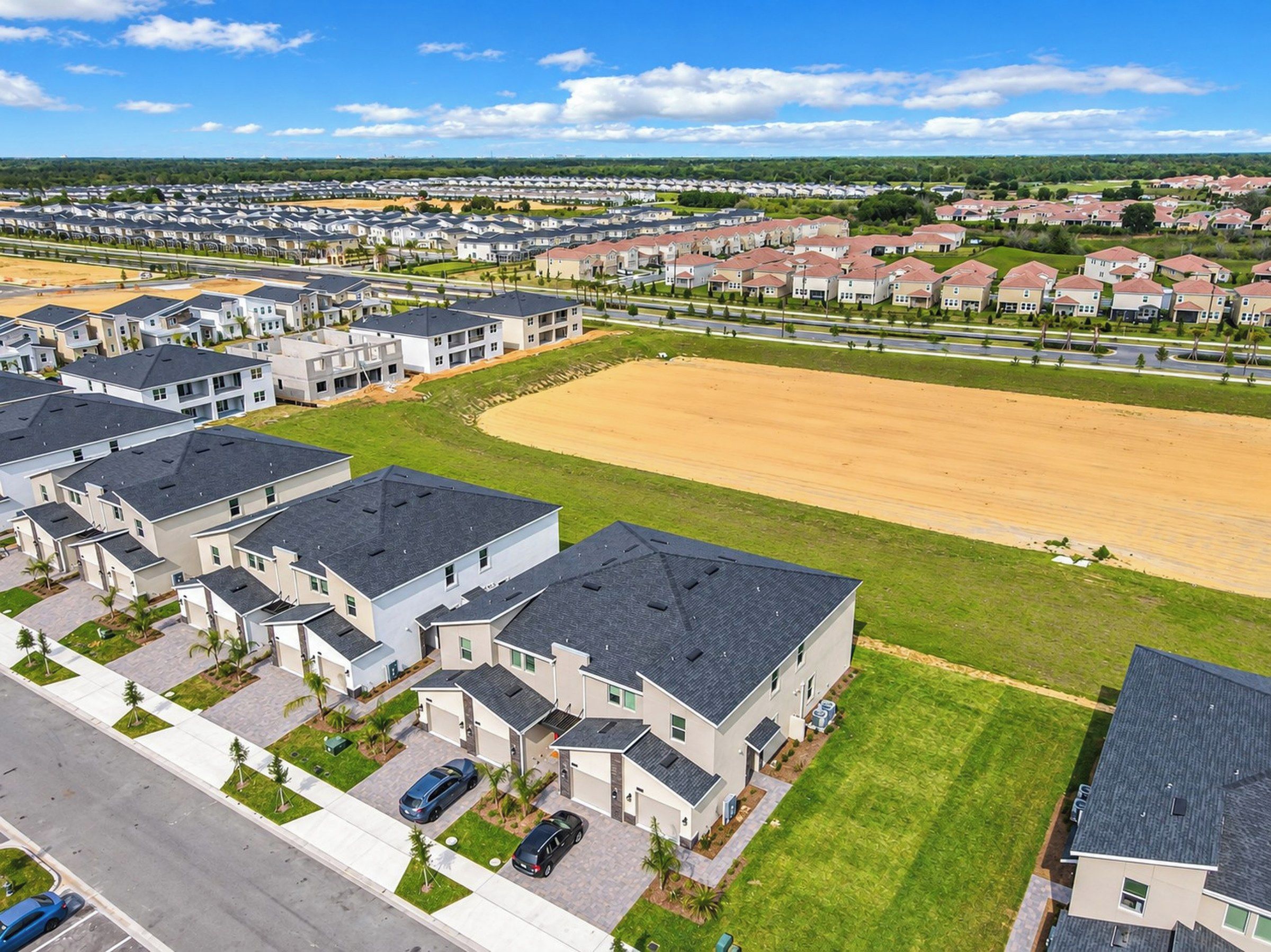 Uma área residencial com casas modernas, um amplo campo aberto e uma rua.