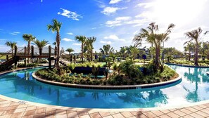 A pool surrounded by palm trees and a wooden bridge.