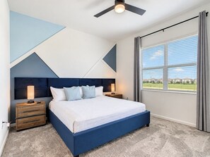 A bedroom with a bed, nightstands, a ceiling fan, and a window with curtains.