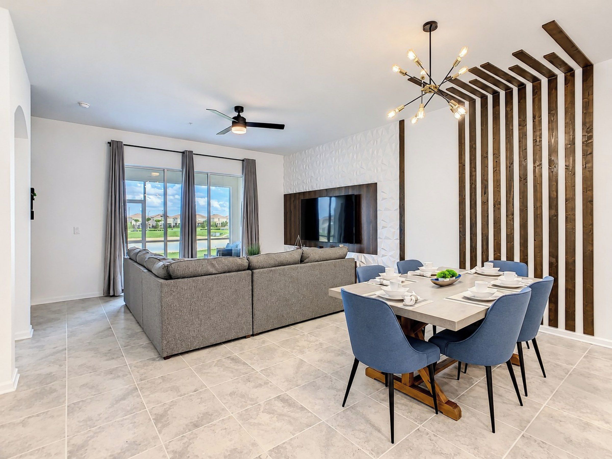 Uma área de refeições moderna com uma mesa grande, cadeiras azuis e um ventilador de teto.