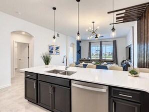 A modern kitchen with a central island, built-in appliances, and pendant lighting.