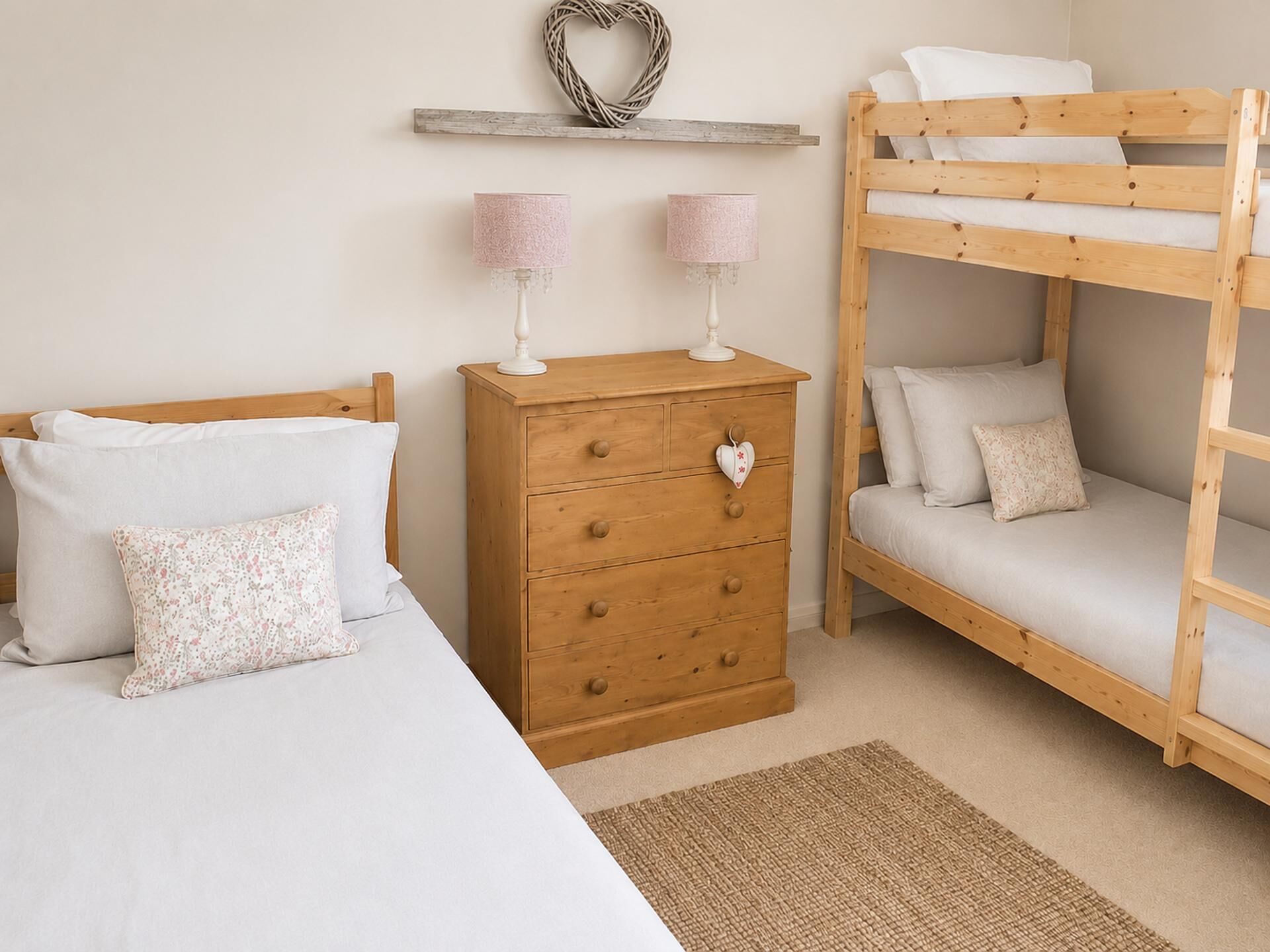 A bedroom with a bunk bed, a wooden dresser with drawers, two lamps, and a heart-shaped lock on the dresser.