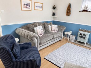 A living room with a grey sofa, blue armchair, and a patterned rug.