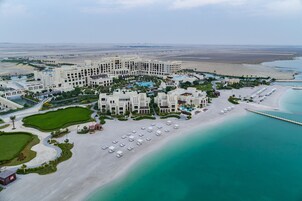 Vista aérea de un complejo turístico con varias construcciones, una playa y una zona de piscina.
