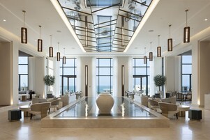 Un vestíbulo amplio con una fuente central, ventanas grandes que ofrecen vistas y luminarias modernas.