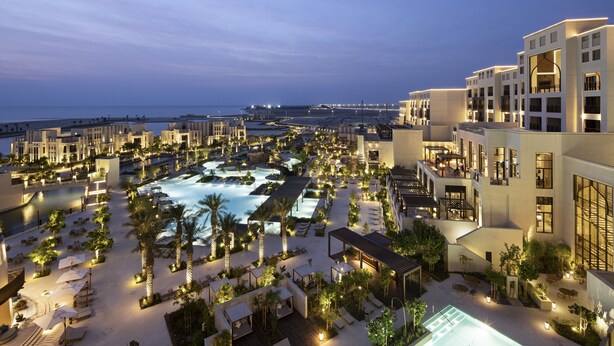 A resort with multiple swimming pools, outdoor seating areas, and a view of the ocean. - Jumeirah Gulf of Bahrain (Zallaq)
