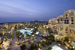 Un resort con varias piscinas, zonas de estar al aire libre y vista al océano.