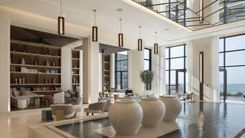 Relax in a spacious, elegantly designed area with comfortable seating, a calming water feature, and natural light pouring in through large windows.